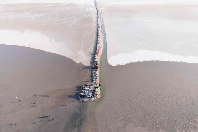 An aerial picture shows Shiite Muslims gathering at a rest stop while walking in Iraq's Basra province on July 19, 2025, as they perform the yearly pilgrimage march, from the southern port city of al-Faw to the holy city of Karbala, ahead of the Arbaeen religious festival. Each year, pilgrims converge in large numbers to the holy Iraqi cities of Najaf and Karbala ahead of Arbaeen, which marks the 40th day after Ashura, commemorating the seventh century killing of Prophet Mohammed's grandson Imam Hussein. (Photo by Hussein Faleh/AFP Photo)