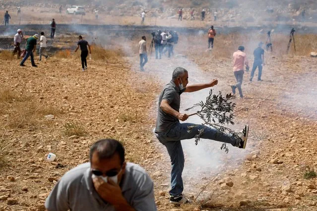 Palestinian demonstrators react to tear gas fired by Israeli forces during a protest against Jewish settlements, in Beit Dajan near Nablus in the Israeli-occupied West Bank on October 9, 2020. (Photo by Raneen Sawafta/Reuters)