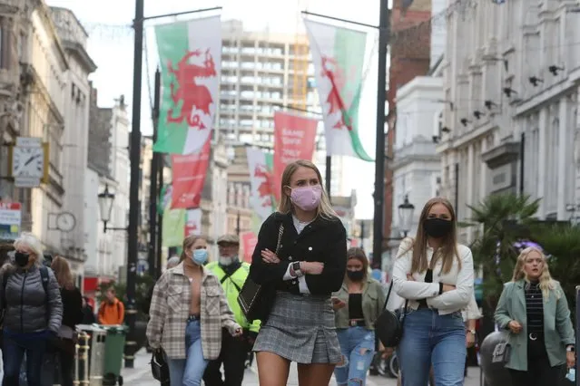People wearing masks because of the coronavirus pandemic are seen in the centre of Cardiff on October 23, 2020, hours before Wales goes into a two-week lockdown. Millions more people headed into coronavirus lockdowns in Britain on Friday, as the government boosted a jobs support package but acknowledged failures in a hugely expensive testing programme. The devolved government in Wales ordered its 3.1 million people to stay at home from 6:00 pm (1700 GMT), closing non-food retailers, cafes, restaurants, pubs and hotels for two weeks. (Photo by Geoff Caddick/AFP Photo)