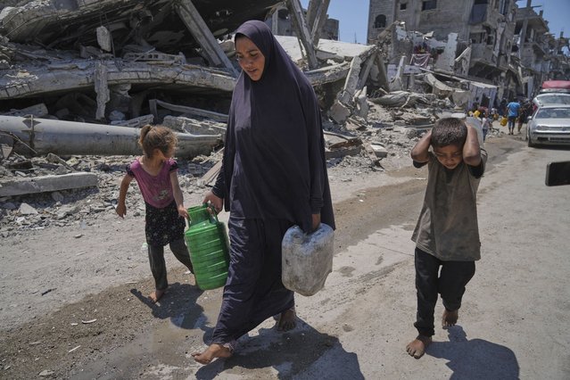 Abeer Sobh and her children carry water in plastic jerrycans after collecting it from a water truck in Gaza City, Thursday, July 24, 2025. (Photo by Jehad Alshrafi/AP Photo)