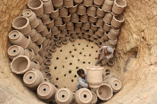 Workers arrange clay pots inside an oven to bake them before putting them up for sale at a factory in Peshawar, Pakistan on July 2, 2025. (Photo by Fayaz Aziz/Reuters)