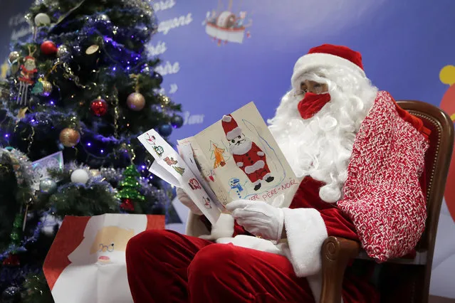 In this Monday, November 23, 2020 file photo, a postal worker dressed as Santa, reads letters to addressed to “Pere Noel” – Father Christmas in French – decorated with love hearts, stickers and glitter, in Libourne, southwest France. Letters pouring by the tens of thousands into Santa's mailbox offer a glimpse into the worries and hopes of children awaiting a pandemic-hit Christmas. Along with usual pleas for toys and gadgets, kids are also mailing requests for vaccines, for visits from grandparents, for life to return to the way it was. (Photo by Francois Mori/AP Photo/File)