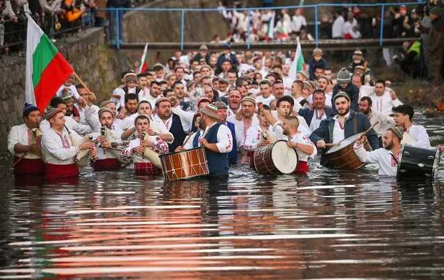 Bulgarian men perform the traditional “Horo” dance in the winter waters of the Tundzha river in the town of Kalofer, as part of Epiphany Day celebrations on January 6, 2023. As a tradition, an Eastern Orthodox priest throws a cross in the river and it is believed that the one who retreives it will be healthy throughout the year as well as all those who dance in the icy waters. (Photo by Nikolay Doychinov/AFP Photo)