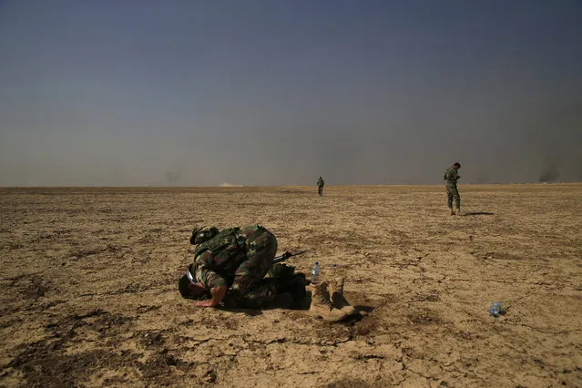 A Kurdish peshmerga fighter prays on the frontline during the battle against the Islamic State group as Kurdish forces advance towards villages surrounding Mosul on Monday, October 17, 2016. The Iraqi military and the country's Kurdish forces say they launched operations to the south and east of militant-held Mosul early Monday morning. (Photo by Bram Janssen/AP Photo)