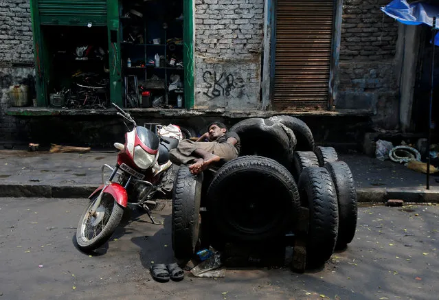 A worker rests on used tyres in front of an automobile repair shop in Kolkata, India, April 10, 2018. (Photo by Rupak De Chowdhuri/Reuters)