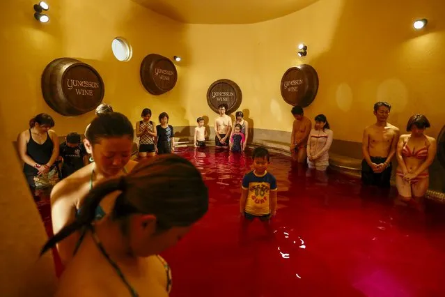 People observe a minute of silence to commemorate the victims of last week's Paris terrorist attack as they stand in a hot bath with coloured water representing wine at the Hakone Kowaki-en Yunessun spa resort during an even marking Beaujolais Nouveau Day in Hakone west of Tokyo, November 19, 2015. (Photo by Thomas Peter/Reuters)