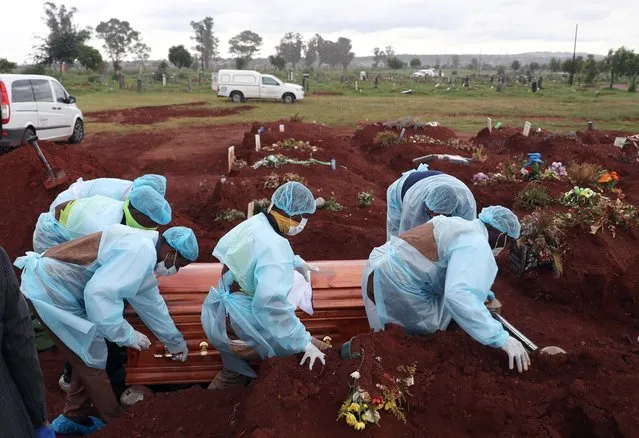 Funeral workers wearing personal protective equipment carry a casket during the burial of a COVID-19 victim at the Olifantsvlei cemetery, south-west of Joburg, South Africa, January 6, 2021. (Photo by Siphiwe Sibeko/Reuters)