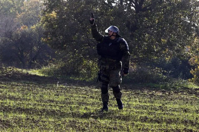A Macedonian police officer shoots in the air as stranded migrants try to cross the Greek-Macedonian border, near Gevgelija, Macedonia December 2, 2015. Picture taken from the Greek side of the border. (Photo by Alexandros Avramidis/Reuters)