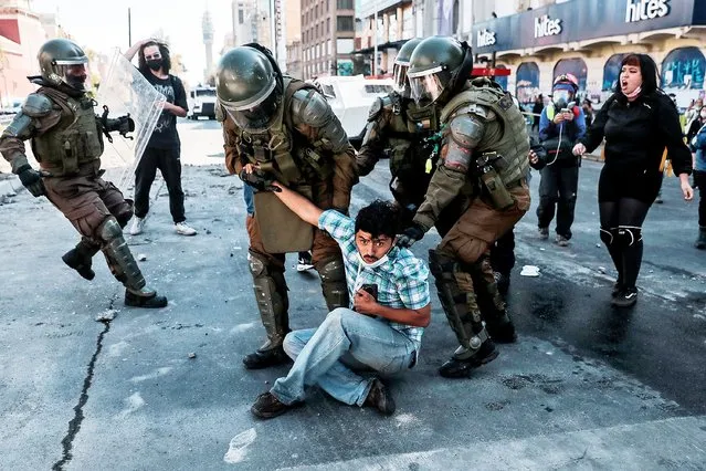 Riot police arrest a demonstrator during a protest to mark the non-official Day of the Young Combatant to raise awareness human rights, in Santiago on March 29, 2022. The date commemorates the assassination of left-wing militant siblings Rafael and Eduardo Vergara at the hands of the police in 1985 during the Augusto Pinochet 1973-1990 dictatorship. (Photo by Javier Torres/AFP Photo)