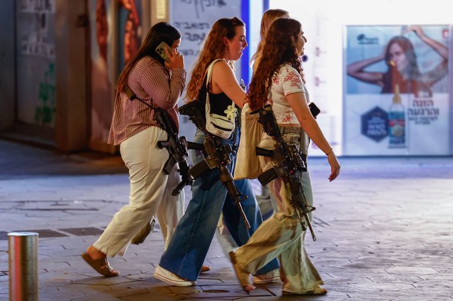 Women carrying rifles walk on Dizengoff Square, amid the ongoing conflict between Israel and Hamas in Gaza and the hostilities between Hezbollah and Israeli forces, in Tel Aviv, Israel, on October 28, 2024. (Photo by Gonzalo Fuentes/Reuters)