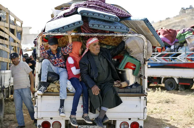 Syrian refugees in the back of a pickup truck get ready to cross into Syria from the eastern Lebanese border town of Arsal, Lebanon, Thursday, June 28, 2018. Dozens of Syrian refugees in Lebanon have started to cross the border, going back home to war-torn Syria. (Photo by Bilal Hussein/AP Photo)