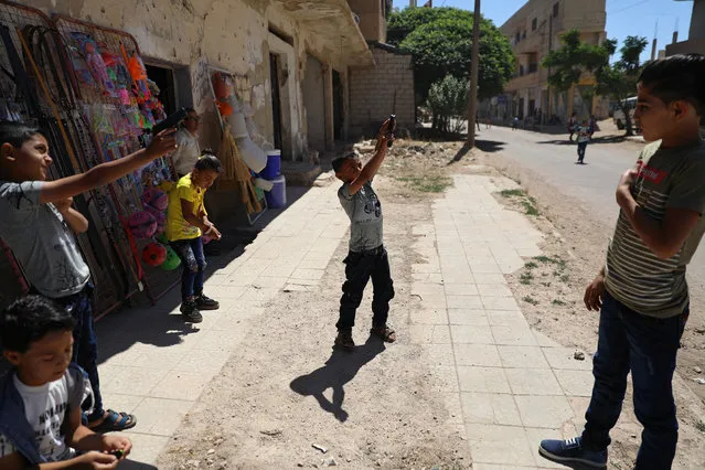 Children play with toy guns on the first day of the Muslim holiday of Eid al-Fitr in the rebel-held town of Dael, Syria June 15, 2018. (Photo by Alaa Al-Faqir/Reuters)