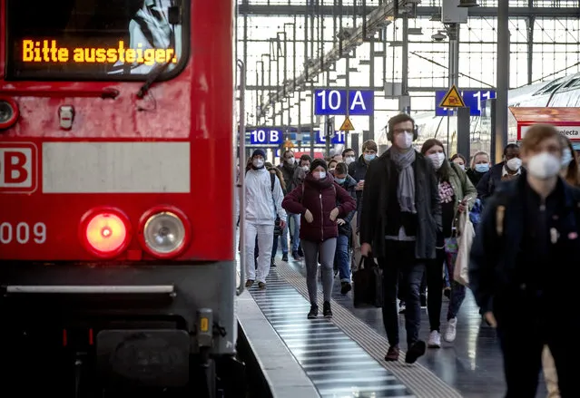 Commuters wearing face masks walk on a platform in the main train station in Frankfurt, Germany, Tuesday, March 2, 2021. German politics discusses further steps to avoid the outspread of the coronavirus. Letters an train read “please disembark”. (Photo by Michael Probst/AP Photo)