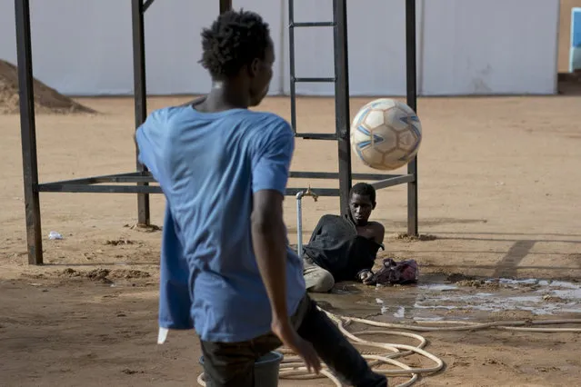 A migrant who was expelled from Algeria watches others play football in a transit center in Arlit, Niger on Friday, June 1, 2018. Traumatized by his experience, he has not spoken and is helped by other migrants for food and bathing. His case puzzles aid workers who cannot find out where he is from in order to repatriate him. (Photo by Jerome Delay/AP Photo)