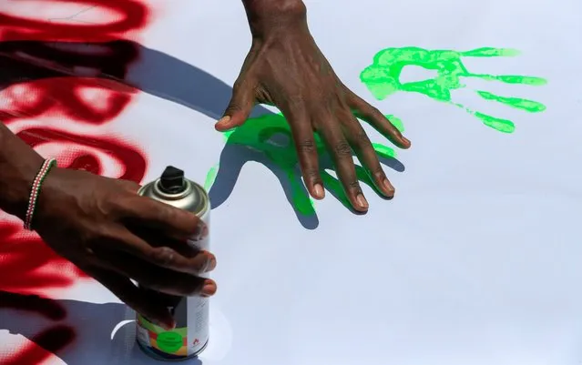 A Fridays For Future activist paints on a banner while participating in a protest demanding actions on climate change, at the John Michuki Memorial Park in Nairobi, Kenya, March 19, 2021. (Photo by Thomas Mukoya/Reuters)