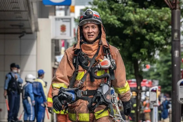 A firefighter works outside of a building where an explosion and a fire broke out in Shimbashi area of Tokyo on July 3, 2023. (Photo by Yuichi Yamazaki/AFP Photo)