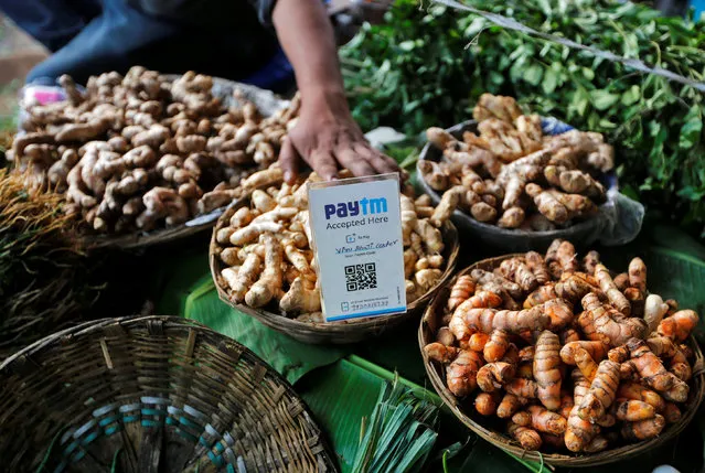 An advertisement board displaying a QR code for Paytm, a digital wallet company, is seen placed amidst vegetables at a roadside vendor's stall in Mumbai, India, November 19, 2016. (Photo by Shailesh Andrade/Reuters)
