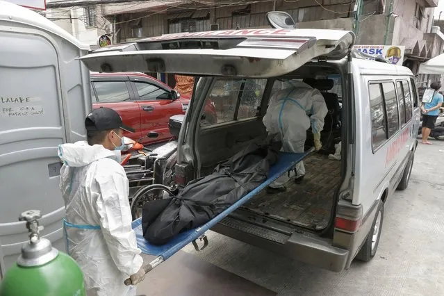 Funeral workers wearing protective suits carry a person who died due to COVID-19 complications at a hospital in Manila, Philippines on Monday, April 26, 2021. COVID-19 infections in the Philippines surged past 1 million Monday in the latest grim milestone as officials assessed whether to extend a monthlong lockdown in Manila and outlying provinces amid a deadly spike or relax it to fight recession, joblessness and hunger. (Photo by Aaron Favila/AP Photo)