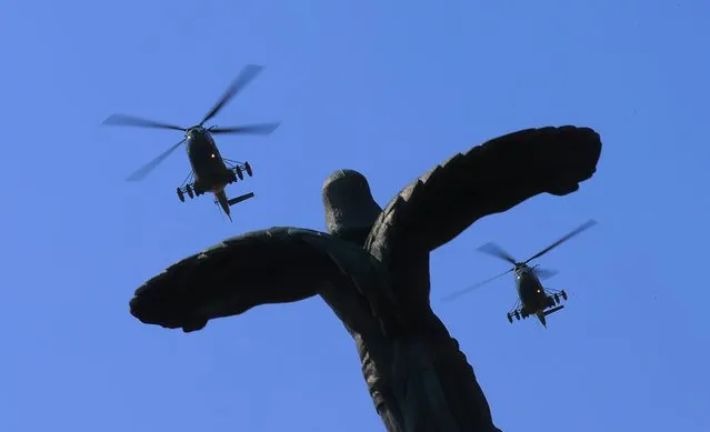 A formation of two military attack helicopters IAR 330 Puma SOCAT belonging to the Romanian Air Force fly over the Statue of Air Heroes during a ceremony marking the Aviation Day and Air Force Day, in Bucharest, Romania, 20 July 2023. The Romanian Aviation and Air Force Day is celebrated every year on 20 July, when the Holy Prophet Elijah, considered the spiritual protector of the pilots, is celebrated by the Romanian orthodox believers. (Photo by Robert Ghement/EPA/EFE)