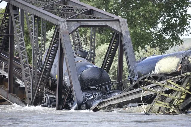 Several train cars are immersed in the Yellowstone River after a bridge collapse near Columbus, Mont., on Saturday, June 24, 2023. The bridge collapsed overnight, causing a train that was traveling over it to plunge into the water below. (Photo by Matthew Brown/AP Photo)