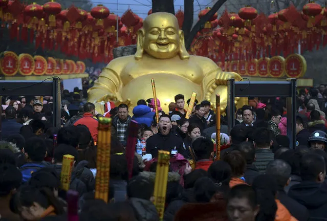 In this Thursday, February 19, 2015 photo, a security guard, center, yawns as visitors crowd the entrance of Badachu Temple during the temple fair for a Lunar New Year celebration in Beijing. (Photo by AP Photo)