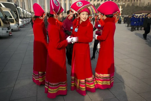 Hostesses gather outside the Great Hall of the People during the opening session of the annual National People's Congress in Beijing, Thursday, March 5, 2015.China announced a lower economic growth target for this year and promised to open more industries to foreign investors as it tries to make its slowing, state-dominated economy more productive. (AP Photo/Mark Schiefelbein)