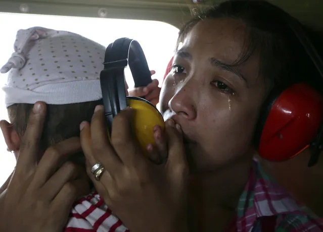 A mother cries in relief upon boarding a Philippine Air Force helicopter, Monday November 11, 2013 following Friday's typhoon Haiyan which lashed Guiuan township, Eastern Samar province, central Philippines. (Photo by Bullit Marquez/AP Photo)