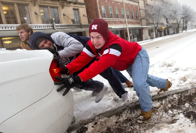 Cole White, right, gets help from Nawaf Khalaf and Kyle Hartley, left, as they attempt to push a vehicle out of snow Tuesday, February 2, 2016, in Lincoln, Neb. A howling storm that dumped more than a foot of snow on some parts of Colorado was laying it on thick in Nebraska and Iowa Tuesday, bringing with it the potential for severe thunderstorms and even tornadoes elsewhere. (Photo by Megan Farmer/Omaha World-Herald via AP Photo)