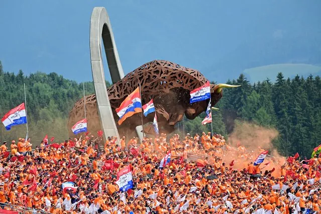 Supporters of Red Bull's Dutch driver Max Verstappen cheer from the stands near the large-scale jumping bull sculpture during the Formula One Austrian Grand Prix at the Red Bull Ring race track in Spielberg, Austria, on July 4, 2021. (Photo by Andrej Isakovic/AFP Photo)