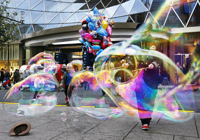 A woman makes bubbles in the main shopping street in Frankfurt, Germany, Tuesday, October 11, 2016. (Photo by Michael Probst/AP Photo)