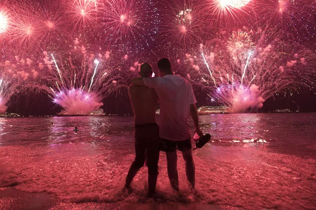 Two men watch the fireworks exploding over Copacabana Beach during the New Year's celebrations in Rio de Janeiro, Brazil, Tuesday, January 1, 2019. (Photo by Leo Correa/AP Photo)
