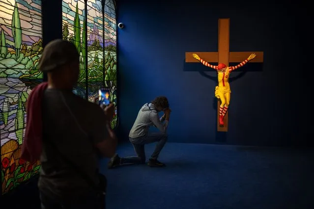 A visitor poses for a photo next to a Jani Leinonen artwork called Mc Jesus, at Barcelona's Museum of Forbidden Art in Barcelona, Spain, Friday, November 17, 2023. In 2019, the Christian community in Haifa demande de removal of Leinonen artwork from the city's museum, considering it offensive. A new museum in Barcelona is offering a second chance to controversial artworks that have suffered censorship for religious, sexual, political or commercial reasons. (Photo by Emilio Morenatti/AP Photo)