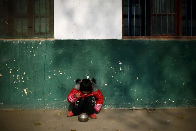 A student eats lunch as she sits on the ground at the Democracy Elementary and Middle School in Sitong town, Henan province December 4, 2013. (Photo by Carlos Barria/Reuters)