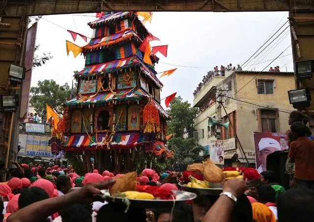 Indian devotees wait with offerings as the chariot carrying an idol of Hindu goddess Muthyalamma passes through a street during the annual festival in her honor in Bangalore, India, Wednesday, April 1, 2015. The 16-day festival is one of the oldest continuously celebrated festivals of Bangalore. (Photo by Aijaz Rahi/AP Photo)