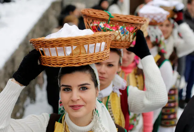 A woman dressed in a traditional folk costume balances a basket of bread on her head during Epiphany day celebration in Bitushe village, Macedonia January 19, 2017. (Photo by Ognen Teofilovski/Reuters)