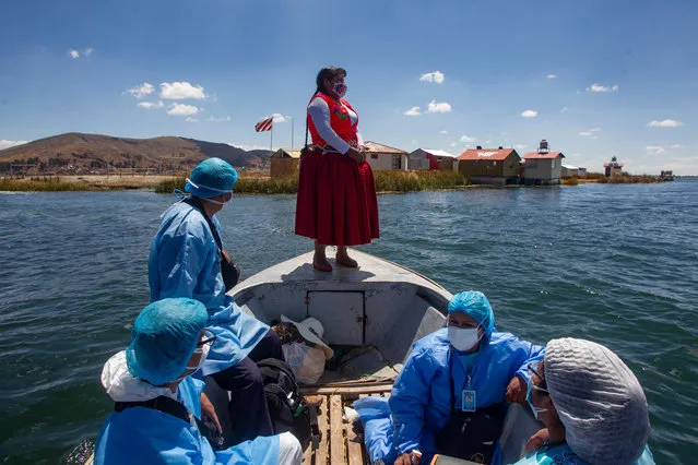 Peruvian Ministry of Health workers accompanied with former Mayor of Uros' island, Inter-cultural manager Rita Subana (C), are seen during a program to immunise vulnerable population that have not yet received anti Covid-19 vaccines at the floating island of Uros in Titicaca lake, Peru on September 12, 2021. More than 1,700 Uros indigenous occupy about 140 islands, of which some are a well known part of the local highland tourist route. “We hope to be immunised in a mass vaccination because we offer lodging and deal every day with national and foreign tourists, and we run risks of being infected”, Nelson Coila, Uros Community president said to AFP. (Photo by Carlos Mamani/AFP Photo)