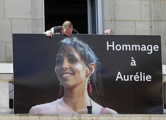 Workers set up a banner showing a portrait of Aurelie Chatelain on the front of the city hall of Caudry, northern France, Wednesday, April 22, 2015. An Islamic extremist with an arsenal of loaded guns was only prevented from opening fire on churchgoers because he accidentally shot himself in the leg, French officials said Wednesday. (Photo by Michel Spingler/AP Photo)