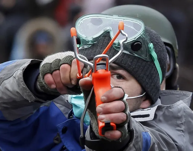 A pro-European integration protester uses a slingshot during clashes with police in Kiev January 20, 2014. Protesters clashed with riot police in the Ukrainian capital on Sunday after tough anti-protest legislation, which the political opposition says paves the way for a police state, was rushed through parliament last week. (Photo by Vasily Fedosenko/Reuters)