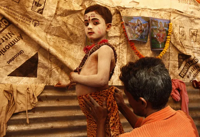 Sumanta Das, 8, is dressed up as Lord Shiva by his father to get alms from pilgrims at a make-shift shelter before an annual trip to Sagar Island for the one-day festival of “Makar Sankranti”, in Kolkata January 11, 2014. Hindu monks and pilgrims make the annual trip to Sagar Island for a holy dip at the confluence of the Ganges river and the Bay of Bengal on January 14. (Photo by Rupak De Chowdhuri/Reuters)
