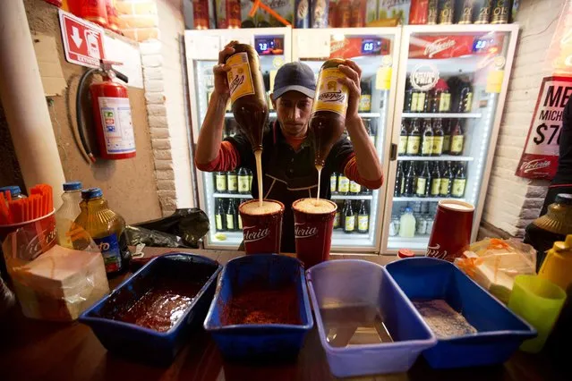 In this April 10, 2015 photo, a vendor prepares micheadas at the Texcoco Fair on the outskirts of Mexico City. Micheladas are iced beer drinks with lime juice, salt and spices. (Photo by Eduardo Verdugo/AP Photo)