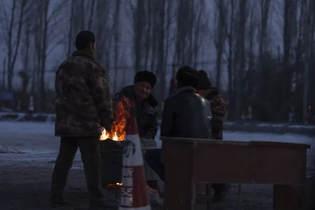 Men gather near a fire at a checkpoint into Wushi county in China's western Xinjiang region on Tuesday, January 23, 2024. A massive earthquake has struck a sparsely populated part of China's western Xinjiang region, killing a few and damaging or collapsing more than 120 homes in freezing cold weather. (Photo by Ng Han Guan/AP Photo)