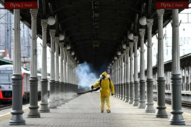A serviceman of Russia's Emergencies Ministry wearing protective gear disinfects Moscow's Belorussky railway station on October 20, 2021, amid the ongoing coronavirus disease pandemic. Russia said Wednesday 1,028 people died of Covid over the past 24 hours, a new record, as President Vladimir Putin mulls introducing nationwide restrictions to curb the spread of the disease. (Photo by Kirill Kudryavtsev/AFP Photo)