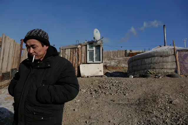 Setevdorj Myagmartsogt smokes a cigarette outside his tent-like ger home, which is heated by coal burning stove, in Ulaanbaatar, Mongolia January 29, 2017. Setevdorj Myagmartsogt lives with his wife, four children and two relatives in his ger near a coal depot not far from the centre of the Mongolian capital. (Photo by B. Rentsendorj/Reuters)