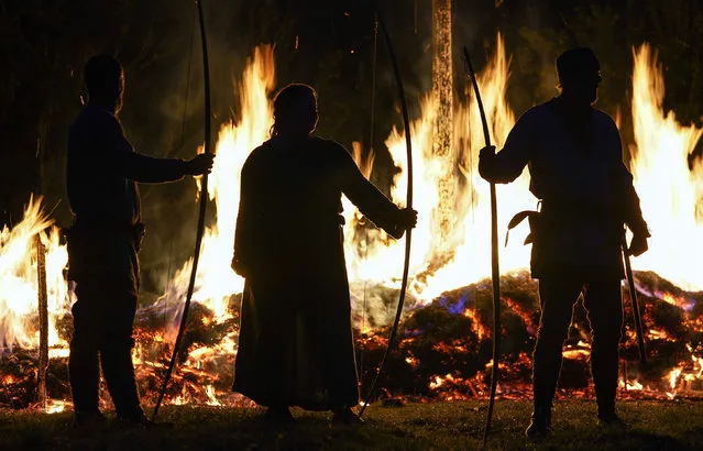 Members of the Herigeas Hundas living history group watch the burning of a ceremonial Viking long boat during the equinox at Butser Ancient Farm in Hampshire, United Kingdom on September 20, 2021. (Photo by Andrew Matthews/PA Wire Press Association)