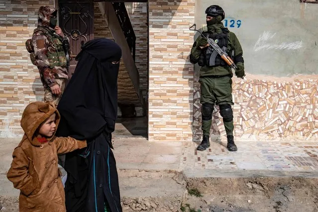 Syrian Kurdish Asayish security forces stand guard outside a house during a raid against suspected Islamic State group fighters in Raqa, the jihadist group's former defacto capital in Syria, on January 29, 2023. After the jihadists lost their last scraps of territory following a military onslaught backed by the coalition in March 2019, IS remnants in Syria mostly retreated into desert hideouts in the country's east. They have since used such hideouts to ambush Kurdish-led forces and Syrian government troops while continuing to mount attacks in Iraq. (Photo by Delil Souleiman/AFP Photo)