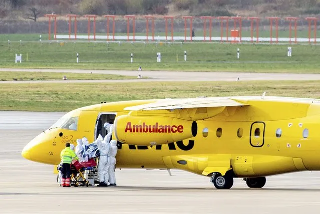 One of two Covid 19 patients is unloaded from a Dornier 328Jet ADAC aircraft by rescue workers at Hanover airport for transfer to hospital by intensive care transport in Langenhagen, Germany, Tuesday, November 30, 2021. Seriously ill patients from intensive care units in Bavaria, Thuringia and Saxony are being transported to areas in the north and west of Germany that are currently less severely affected as part of the “cloverleaf” mechanism coordinated between the federal and state governments throughout Germany. (Photo by Hauke-Christian Dittrich/dpa via AP Photo)