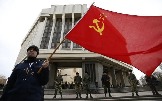 A man holds a Soviet Union flag as he attends a pro-Russian rally at the Crimean parliament building in Simferopol March 6, 2014. The decree making Crimea part of Russia is already in force and Ukrainian troops still on its territory will be treated as occupiers and forced to surrender or leave, the Russian-controlled region's deputy prime minister said. (Photo by David Mdzinarishvili/Reuters)