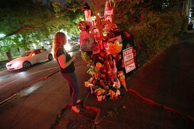 Jacquelyn Brubaker, of New Orleans, looks at a makeshift memorial Monday, April 11, 2016, near the spot where former New Orleans Saints defensive end Will Smith was shot and killed, and his wife was wounded by gunfire, after a traffic accident in New Orleans on Saturday. (Photo by Gerald Herbert/AP Photo)