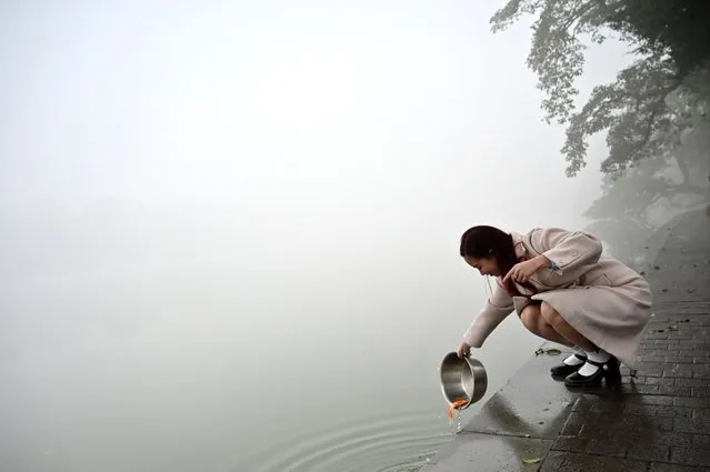A woman releases a fish into a lake on a foggy morning in Hanoi on February 2, 2024. (Photo by Nhac Nguyen/AFP Photo)