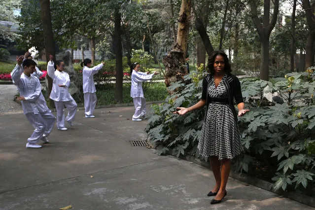First Lady Michelle Obama gestures as she watches students practice Taichi at Chengdu No. 7 High School during her visit in Chengdu, China. (Photo by Petar Kujundzic/Reuters)